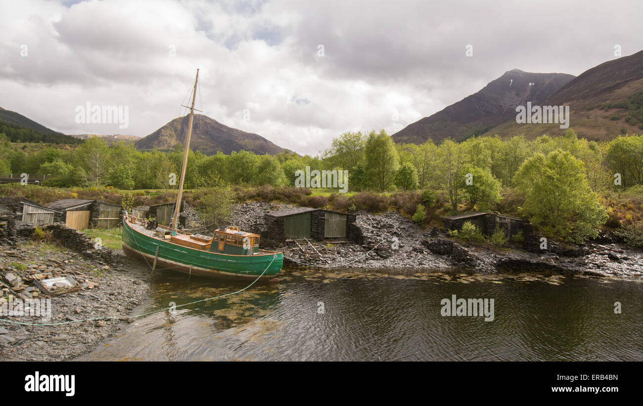 Verniciato di verde barca di legno a Ballachulish, Loch Leven, ormeggiata davanti a vecchi lavoratori ardesia' boatsheds Foto Stock