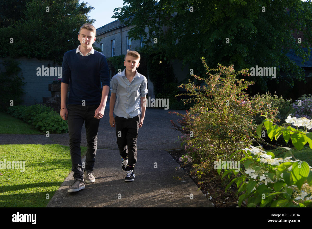 Due fratelli a piedi verso la telecamera in una bella luce della sera Foto Stock