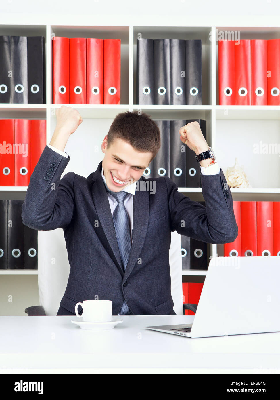 Fiducioso giovane impreditore trionfo guardando al laptop Foto Stock