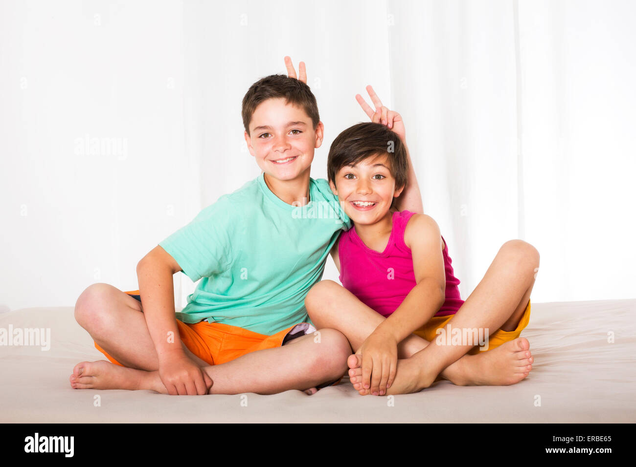 Due ragazzi seduti nel letto e sorridente Foto Stock