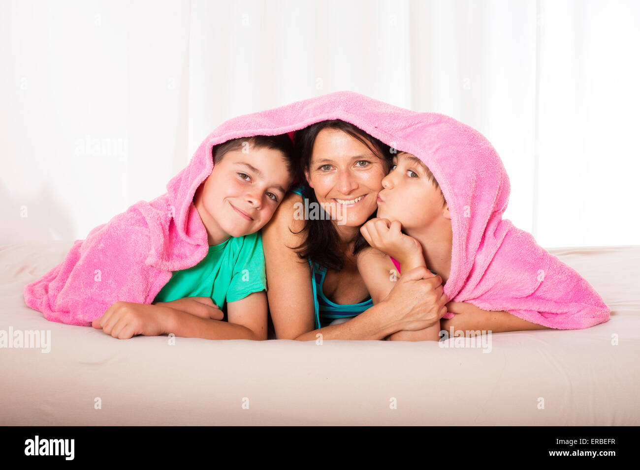 La madre ed i suoi figli sono giacenti nel letto e sorridente Foto Stock