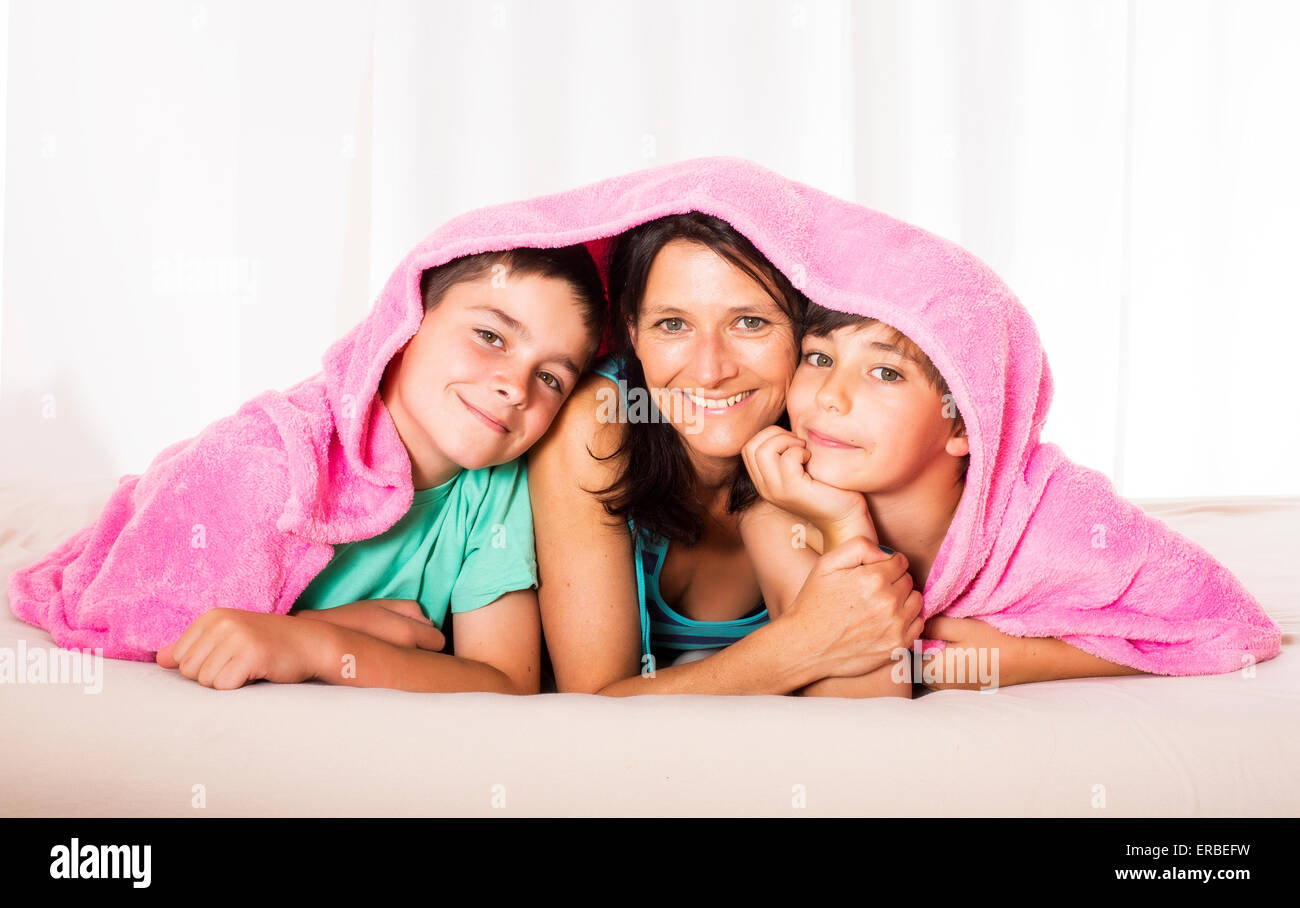La madre ed i suoi figli sono sdraiato sul letto e ridendo Foto Stock