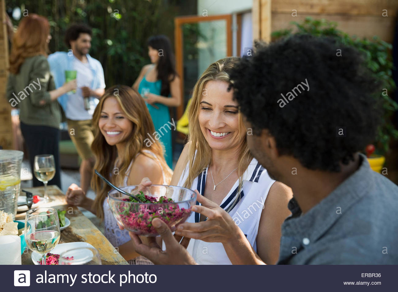 Gli amici di mangiare e passando il cibo in tavola patio Foto Stock