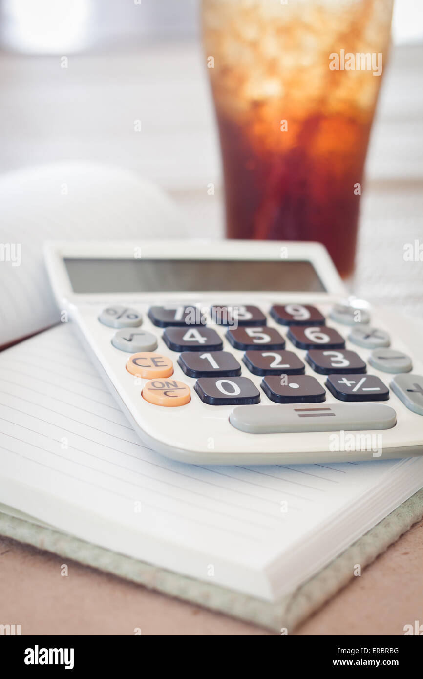 Calcolatrice sul notebook vuota con un bicchiere di coca cola, stock photo Foto Stock