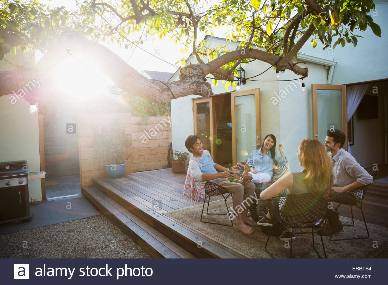 Gli amici a bere e a parlare sul patio soleggiato Foto Stock