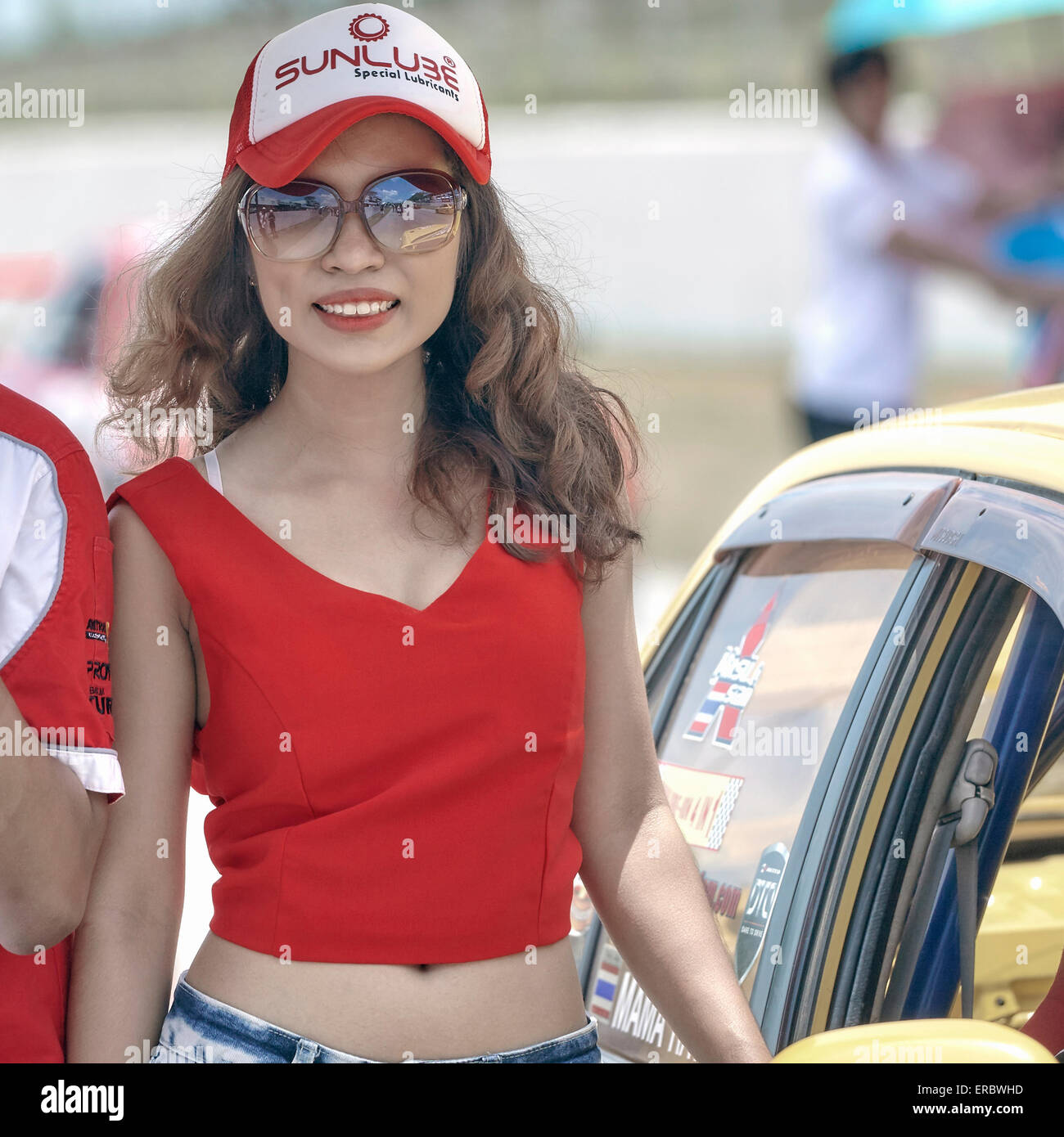 Donna asiatica, attraente e sorridente, che funge da padrona di casa in pista ad un evento Motorsport. Foto Stock