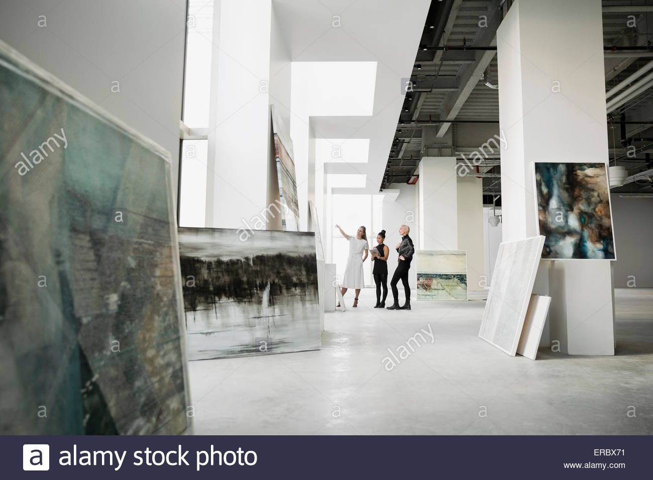 Artista e i commercianti di opere d'arte a discutere di dipinti art gallery Foto Stock