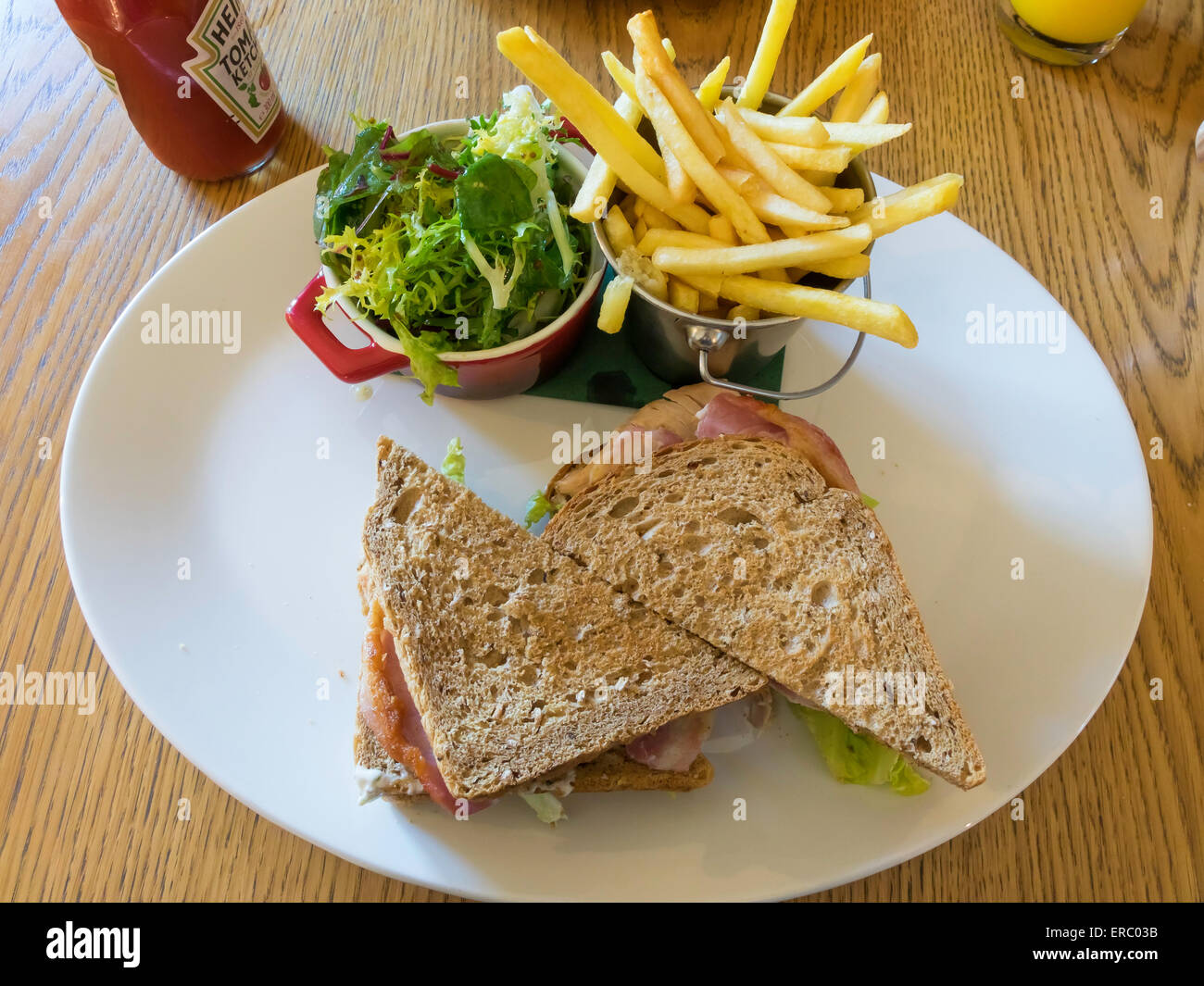 Café il pranzo a due- strato club sandwich di pane marrone con pancetta insalata di pollo al pomodoro e mayo con insalata e patatine fritte Foto Stock