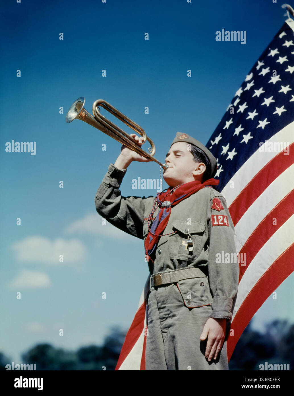 Anni Cinquanta boy scout soffiando BUGLE DAVANTI A 48 stelle della bandiera americana Foto Stock