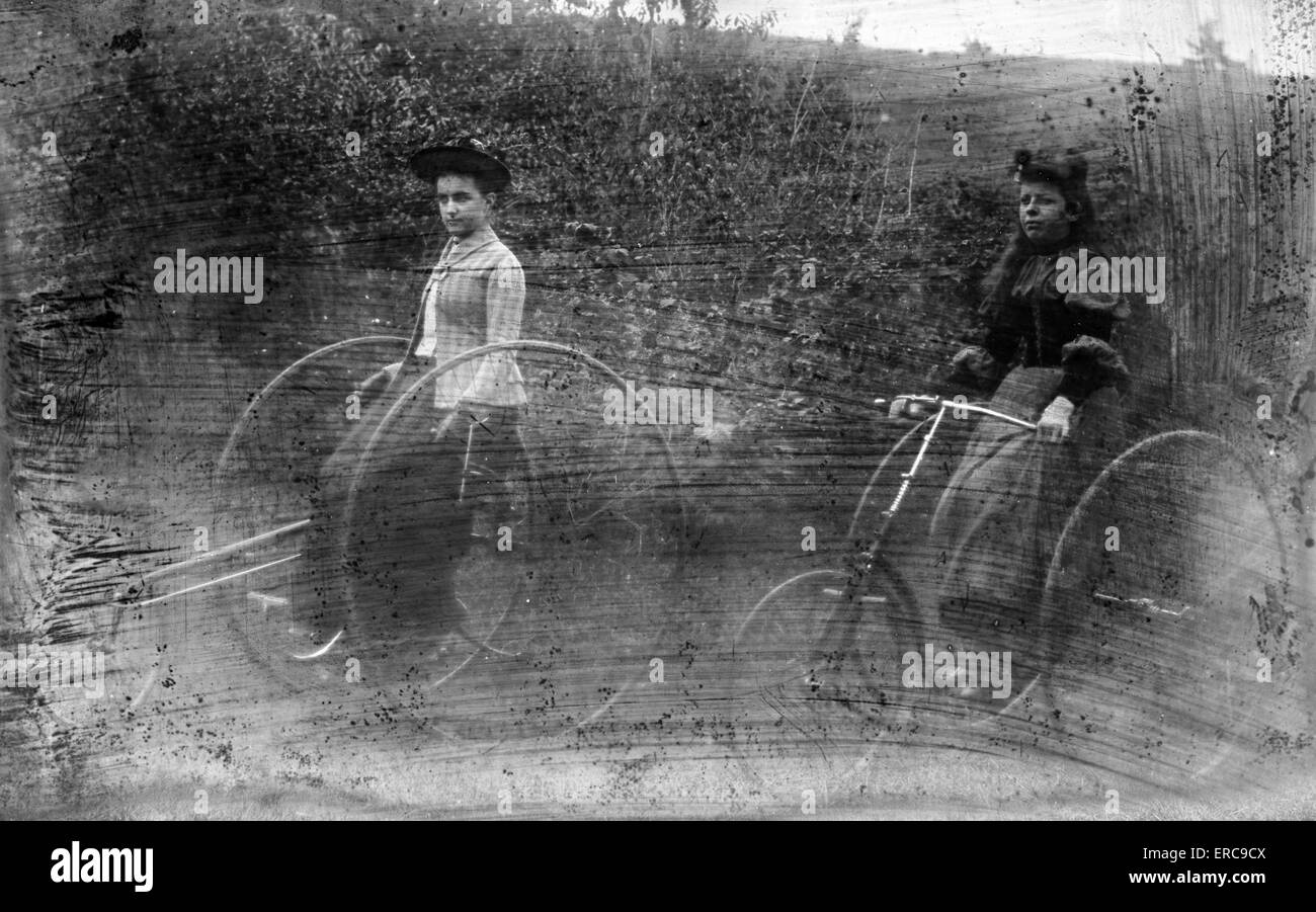 1900s due ragazze tricicli di equitazione sul prato LASTRA DI VETRO gravemente graffiato Foto Stock