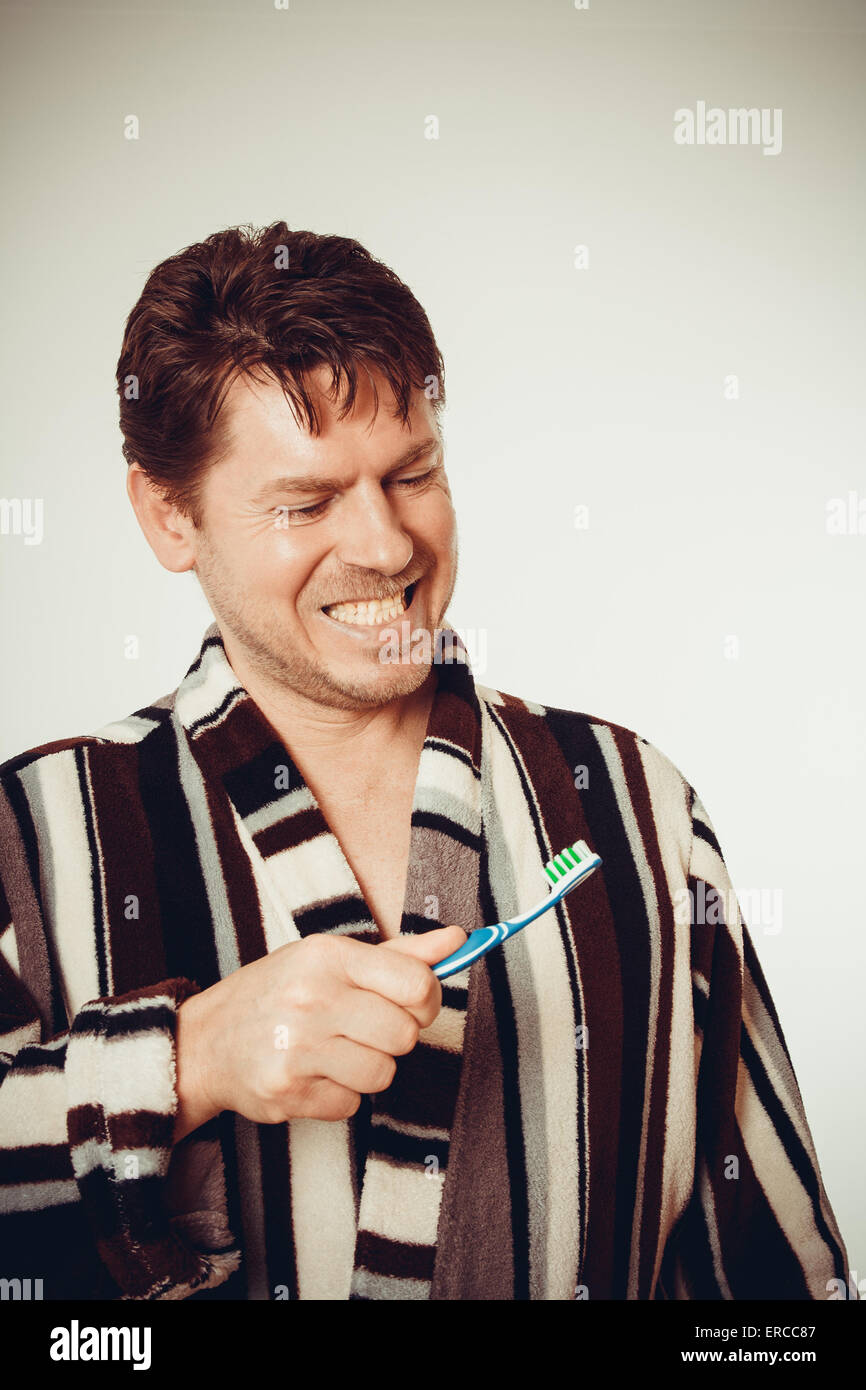 Giovane uomo in accappatoio spazzolare i denti in look vintage Foto Stock