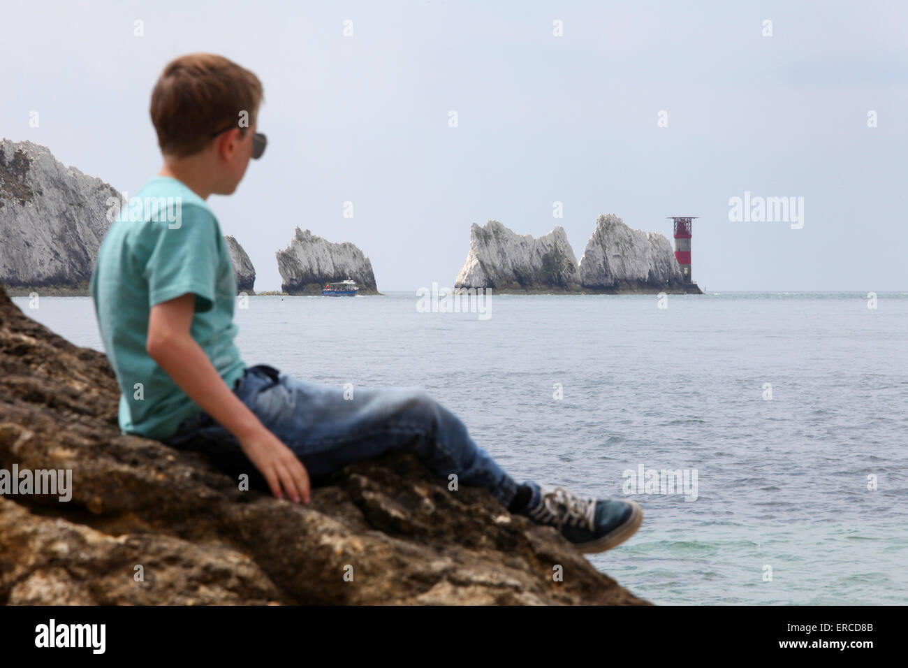 Un ragazzo su una roccia godendo della vista con gli aghi sul isola di Wight (punto di messa a fuoco sugli aghi) Foto Stock