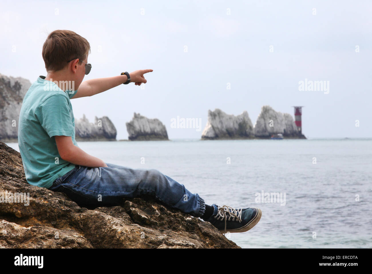 Un ragazzo su una roccia godendo della vista con gli aghi sul isola di Wight (punto di messa a fuoco sul boy) Foto Stock