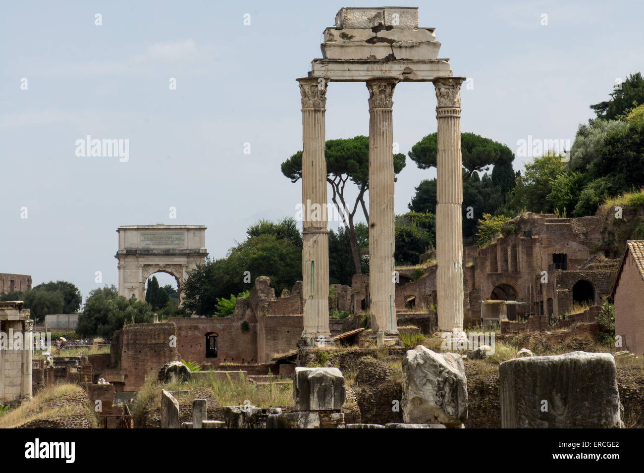 Tre colonne rimanenti dal tempio di Castore e Polluce, nel Foro Romano, Roma. Arco di Tito in background. Foto Stock