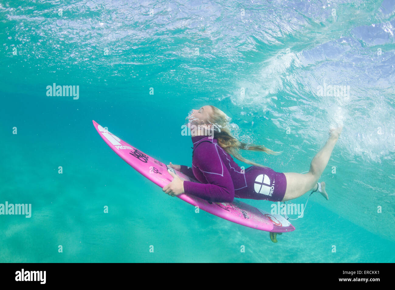 Foto subacquee di una bionda surfer girl con un breve anatra muta immersione sotto un'onda Foto Stock