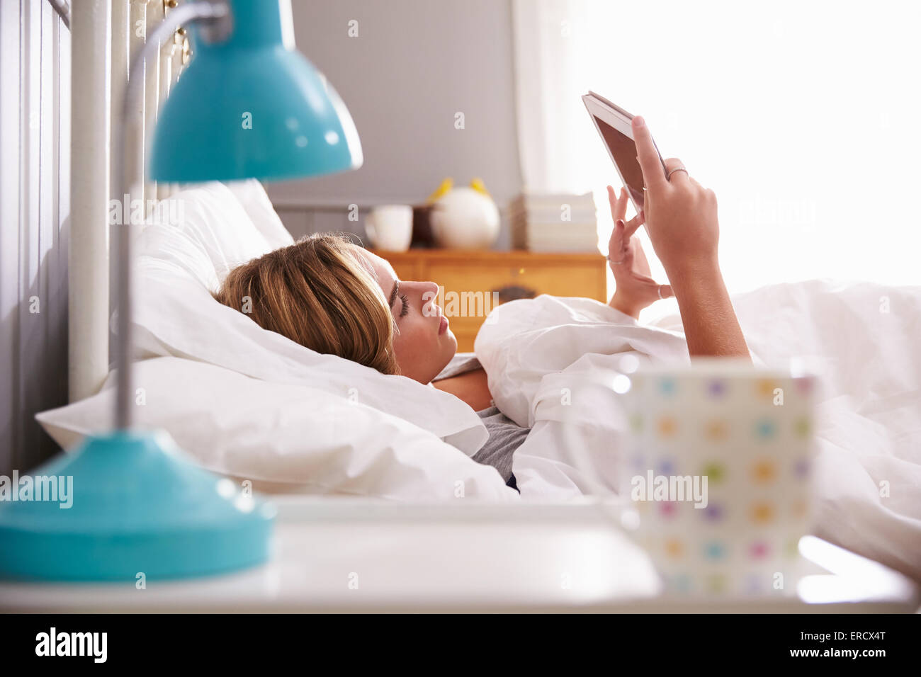 La donna a letto guardando a tavoletta digitale Foto Stock