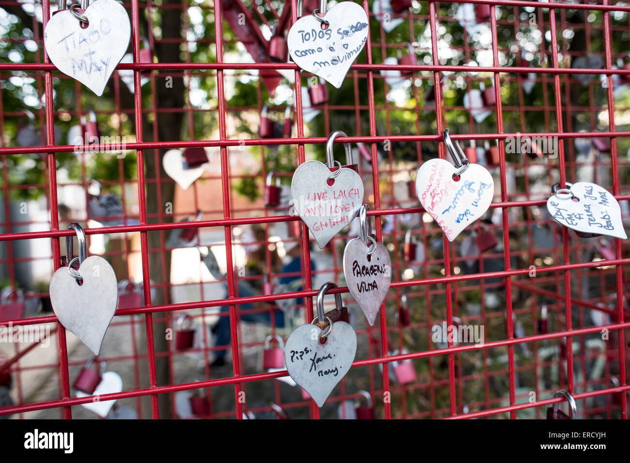 Cuori di metallo con nomi bloccato su un recinto rosso Foto Stock