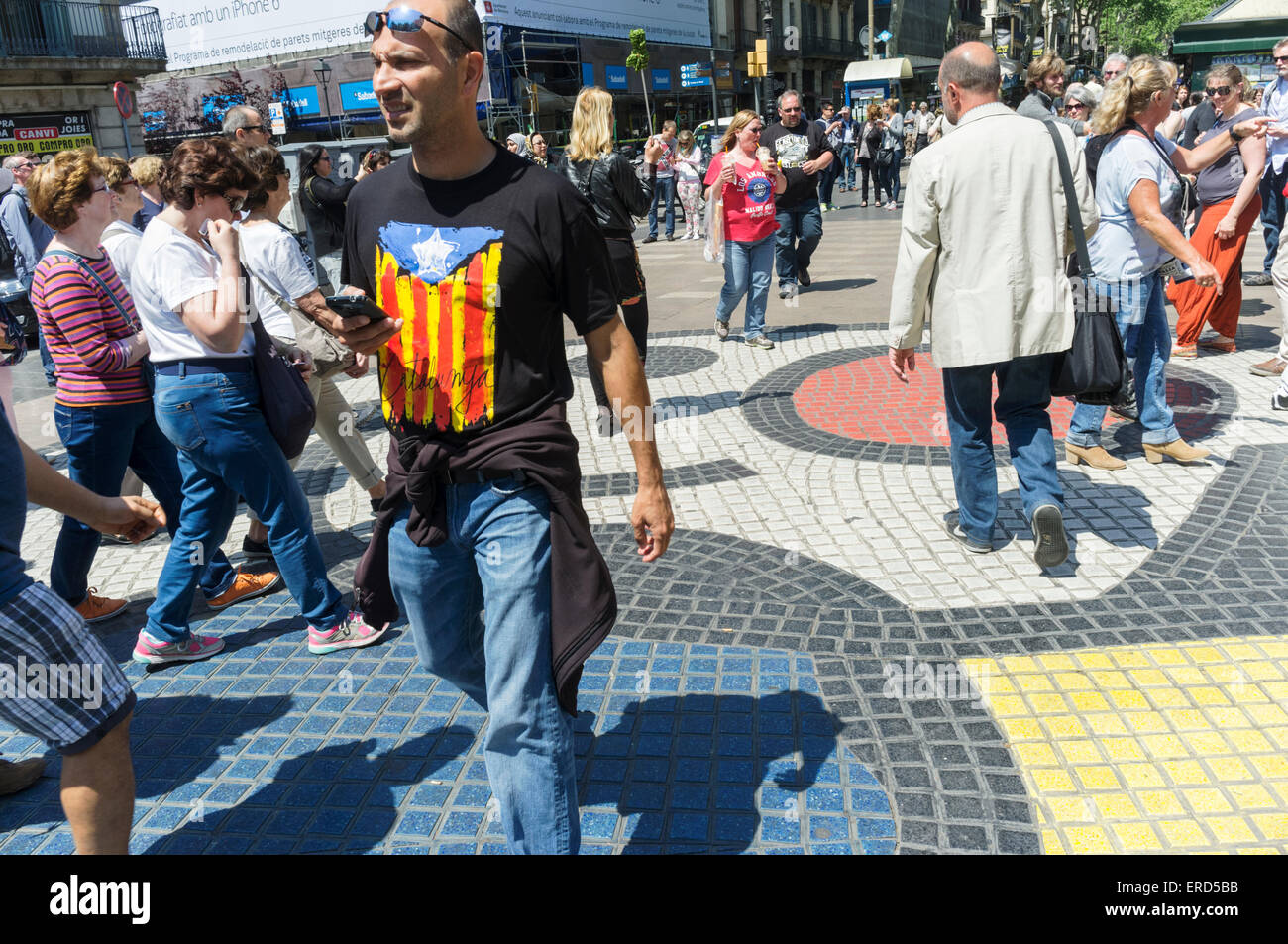 Uomo con un pro-indipendenza senyera bandiera estelada T-shirt camminando sul marciapiede di mosaico di Joan Miró sulla Rambla, Barcelona, Spagna Foto Stock