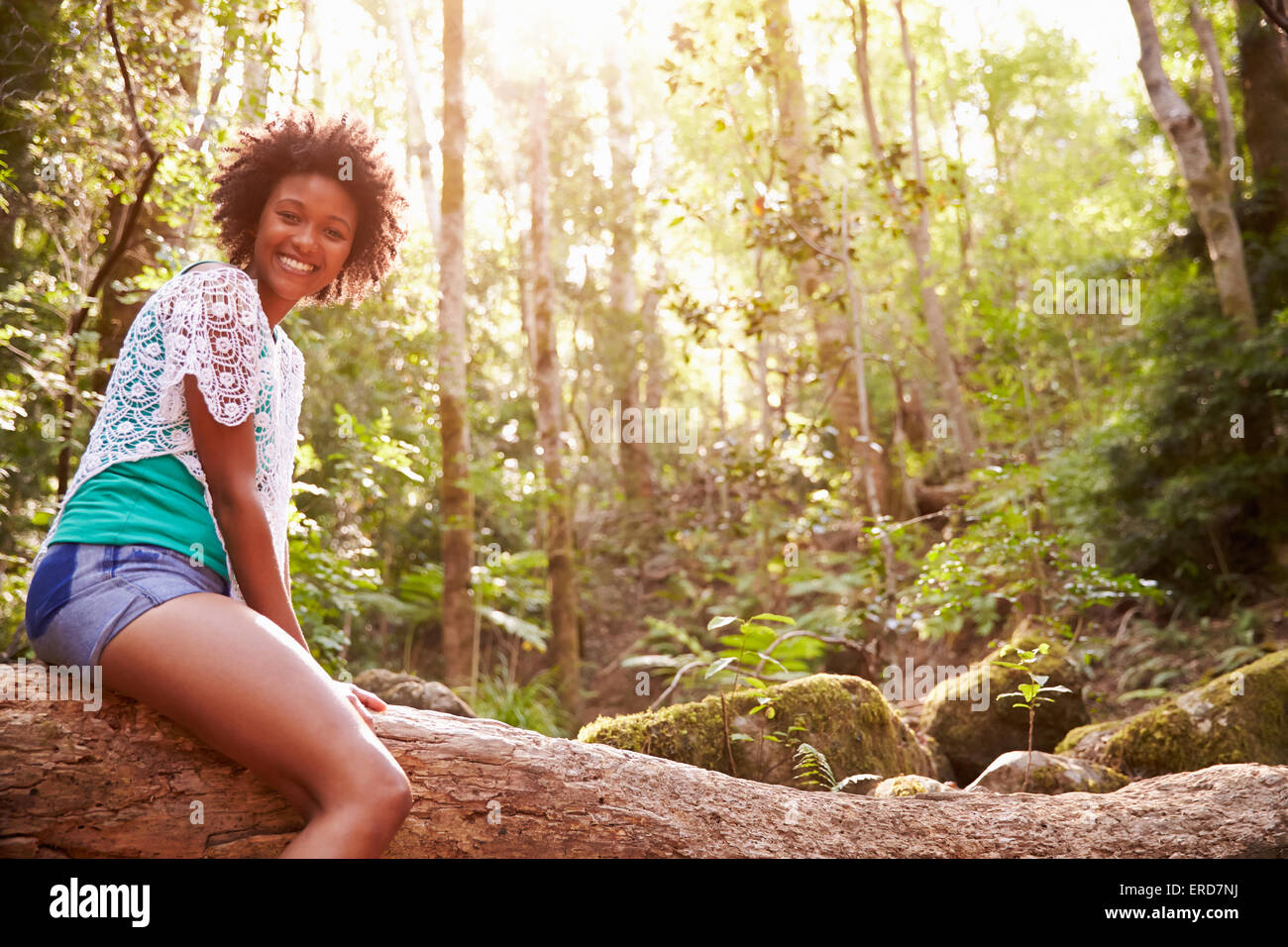 Ritratto di donna seduta sul tronco di albero nella foresta Foto Stock