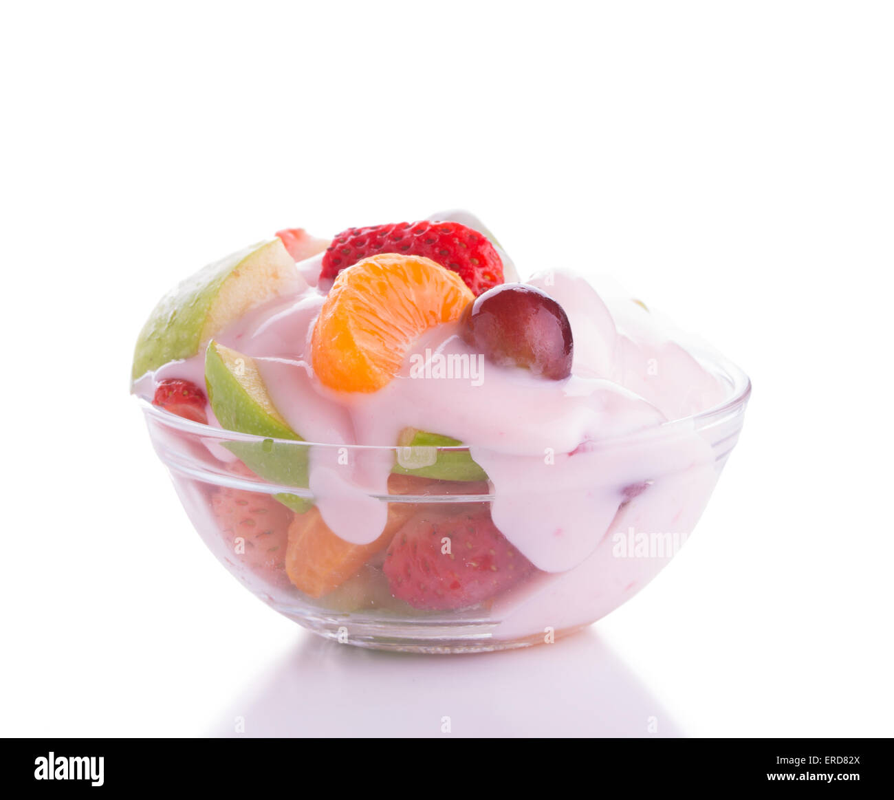 Colorata insalata di frutta in una ciotola di vetro, guarnita con rosa di yogurt alla fragola, su sfondo chiaro Foto Stock