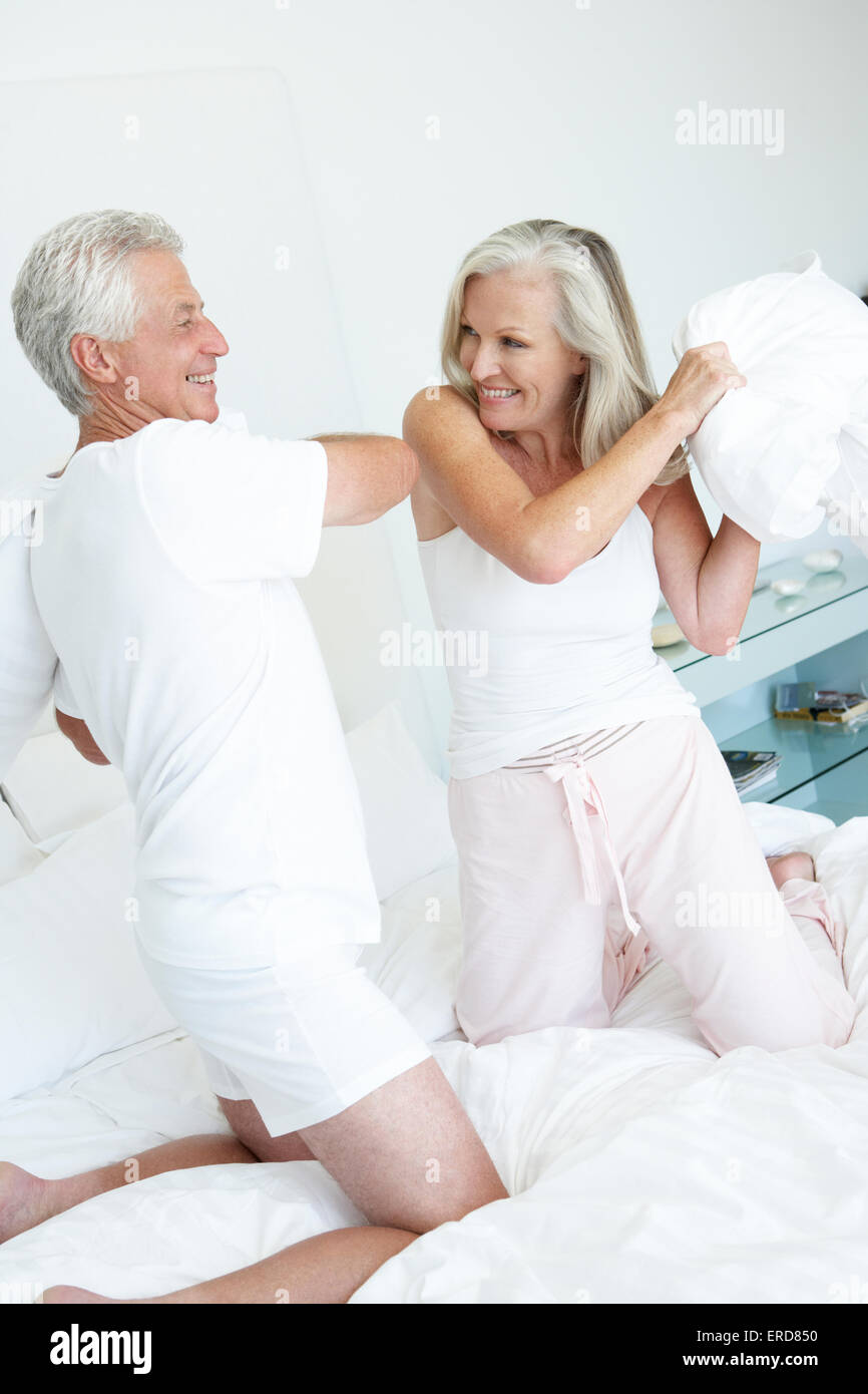 Coppia senior in camera da letto avente pillow fight Foto Stock