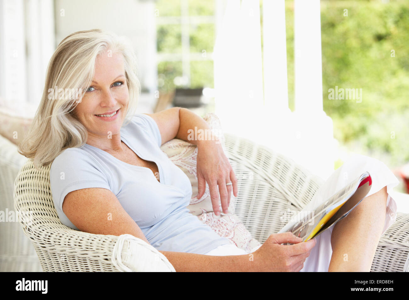 Senior donna seduta al di fuori del magazzino di lettura Foto Stock