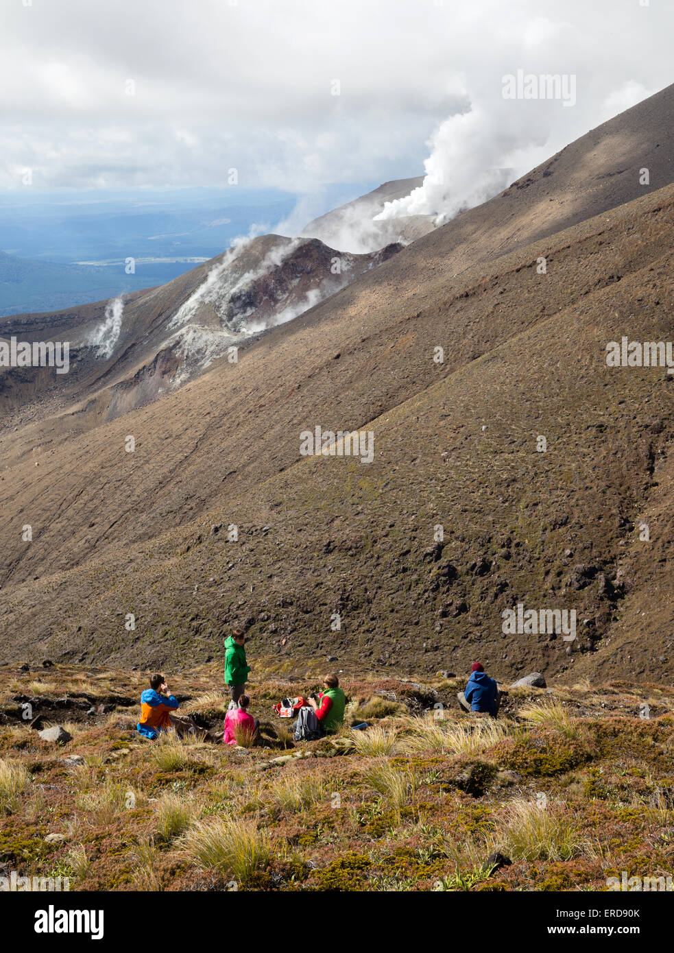 Walkers fermarsi a guardare il vapore ascendente dal vulcanico attivo sui fianchi del monte Tongariro nel Parco Nazionale di Tongariro in Nuova Zelanda Foto Stock