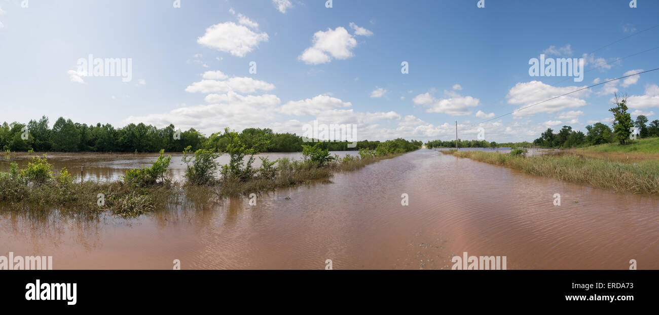 Panorama di una strada rurale completamente inondati con acque di esondazione, con pascoli sulla sinistra sotto l'acqua dopo forti piogge Foto Stock