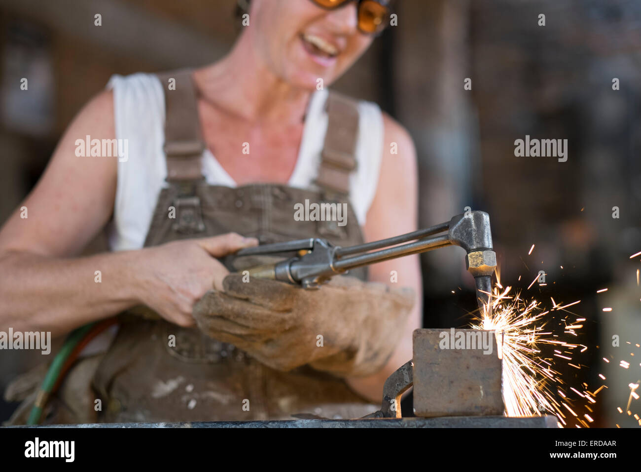 Lavoratore di sesso femminile che utilizzando la torcia di saldatura, con la fiamma creazione di scintille di metallo Foto Stock