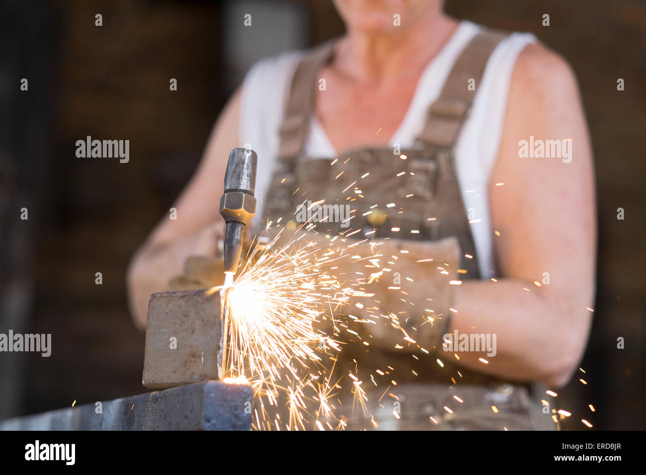 Saldatore con torcia di saldatura in un negozio di metallo. La formazione di scintille sono battenti. Foto Stock