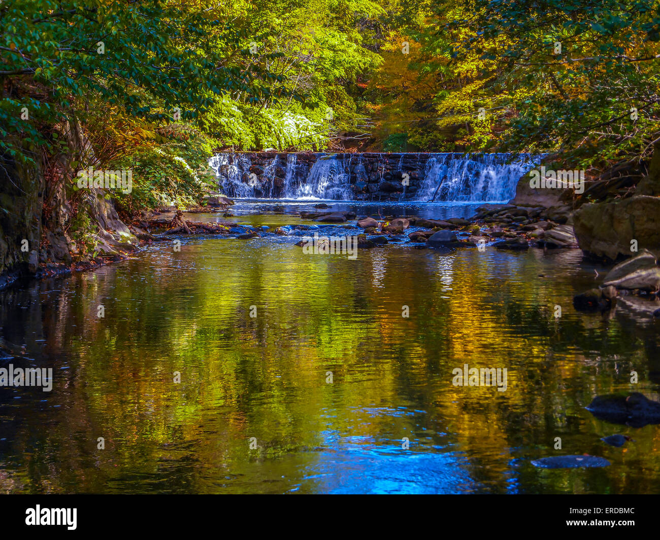 Cascata in una impostazione di autunno con la caduta delle foglie e riflessioni sul fiume utilizzando deep focus Foto Stock