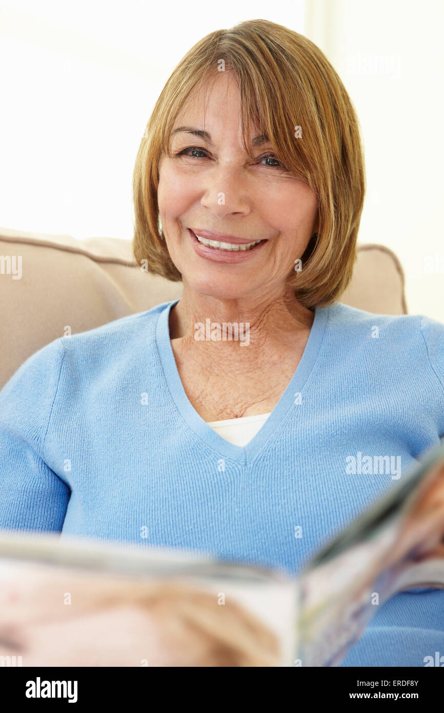 Senior donna ispanica in un momento di relax a casa con la rivista Foto Stock