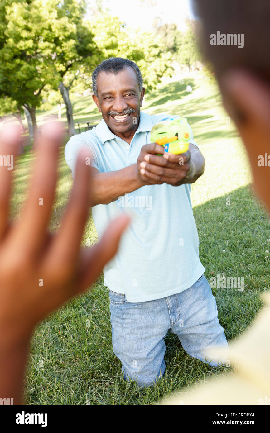 African American nonno e nipote a giocare con le pistole ad acqua in posizione di parcheggio Foto Stock