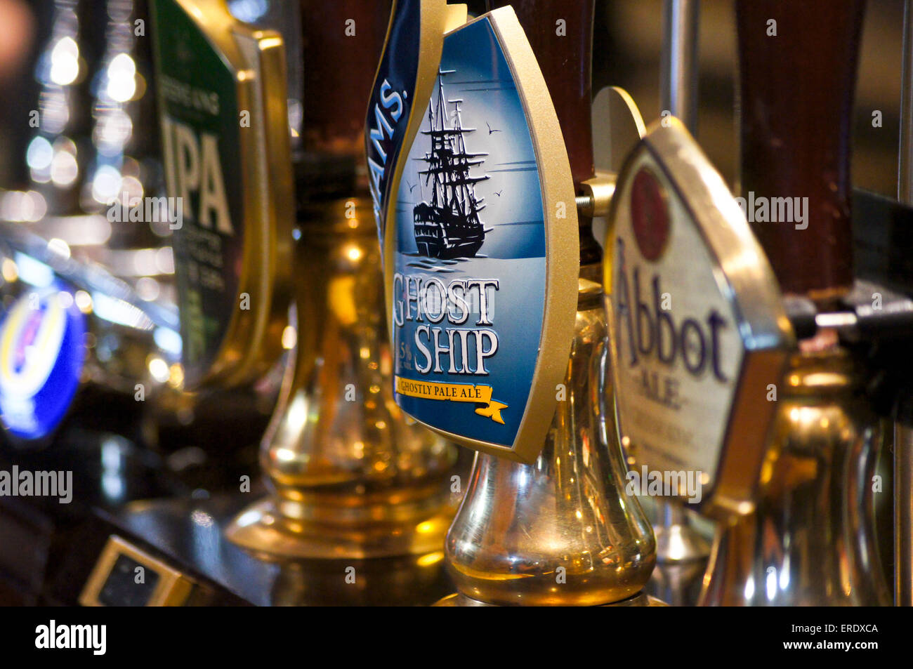 Real ale handpumps e le graffe della pompa su un pub bar- Adnams nave fantasma, la Greene King IPA e Abate Ale Foto Stock