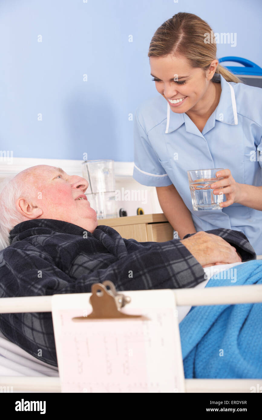 L'infermiera dando un bicchiere di acqua per senior uomo in ospedale Foto Stock