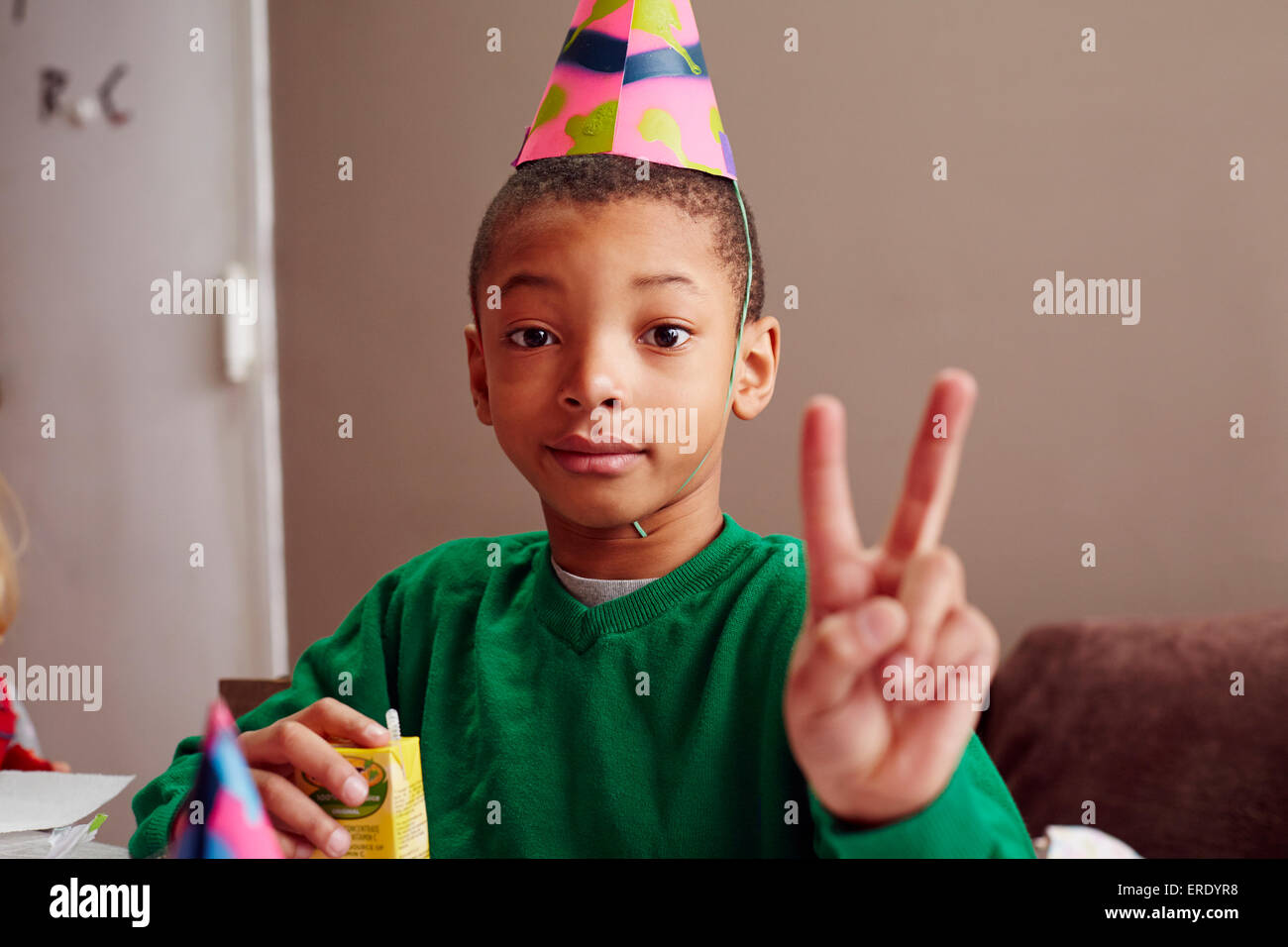 Black Boy indossando party hat facendo segno di pace Foto Stock