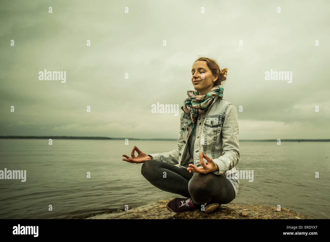 La donna caucasica meditando vicino oceano Foto Stock