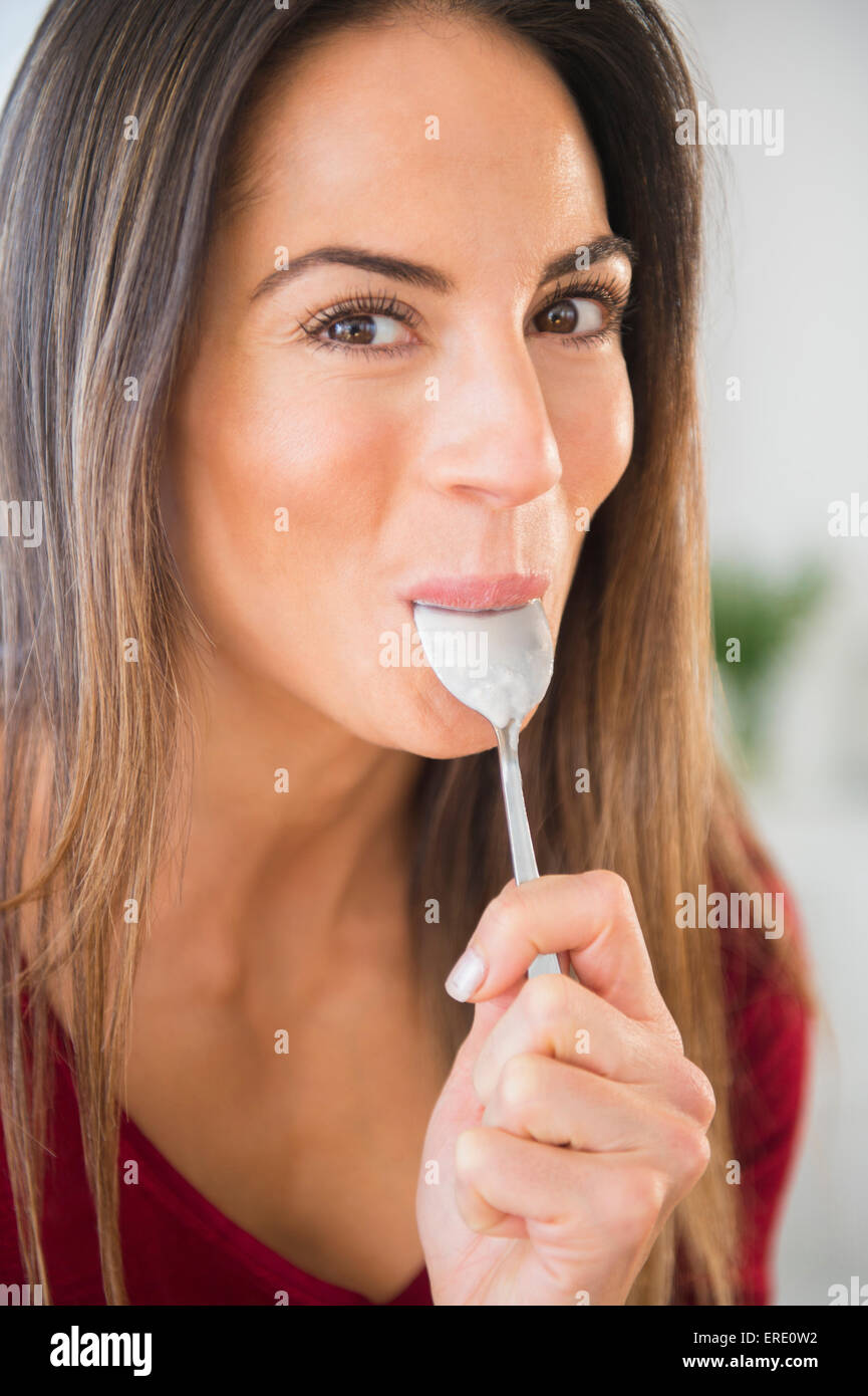 Sorridente donna caucasica leccare il cucchiaio Foto Stock