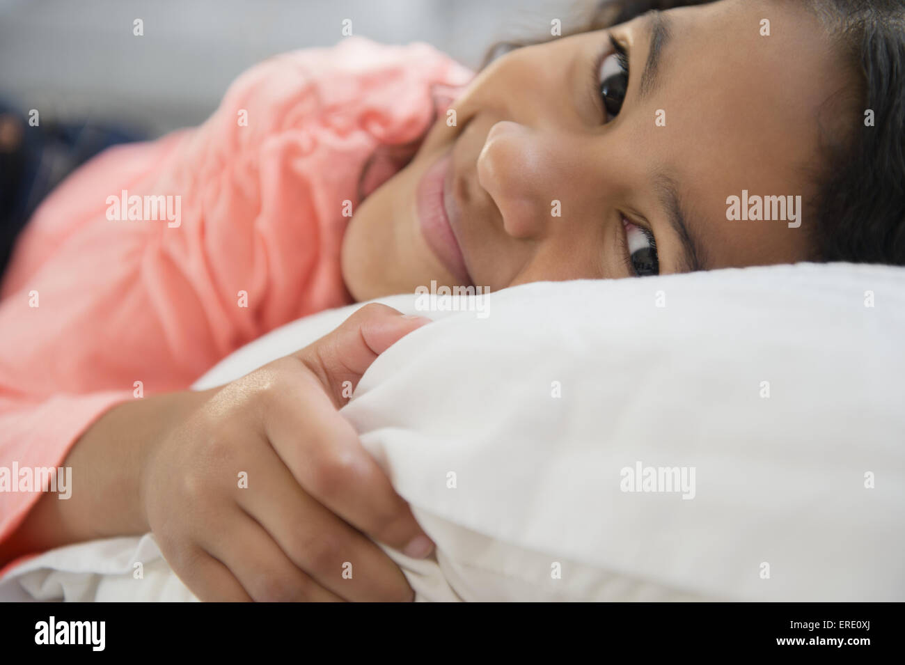 Close up di razza mista ragazza sorridente sul cuscino Foto Stock