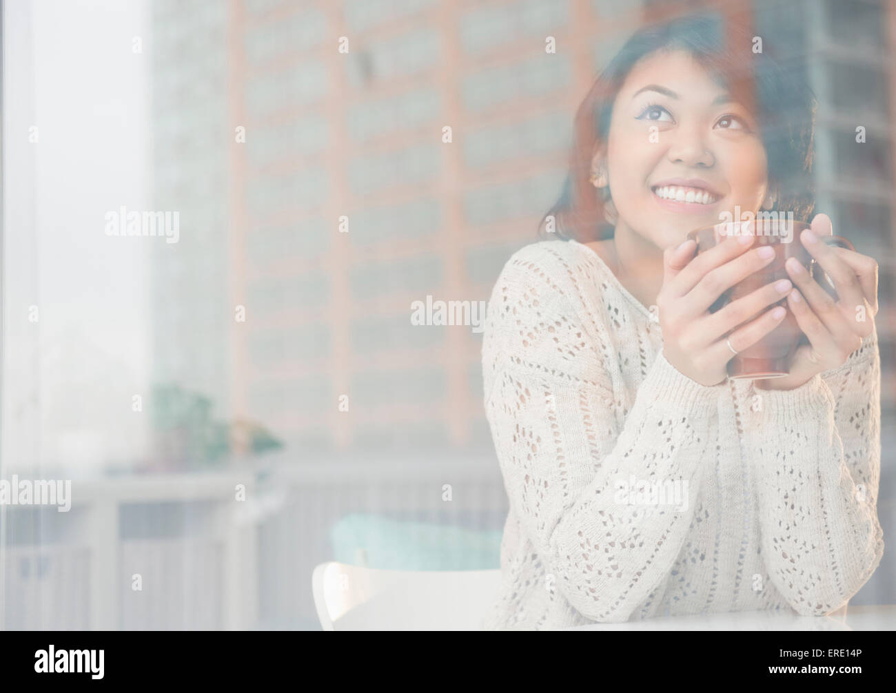 Pacific Islander donna bere caffè dietro la finestra Foto Stock