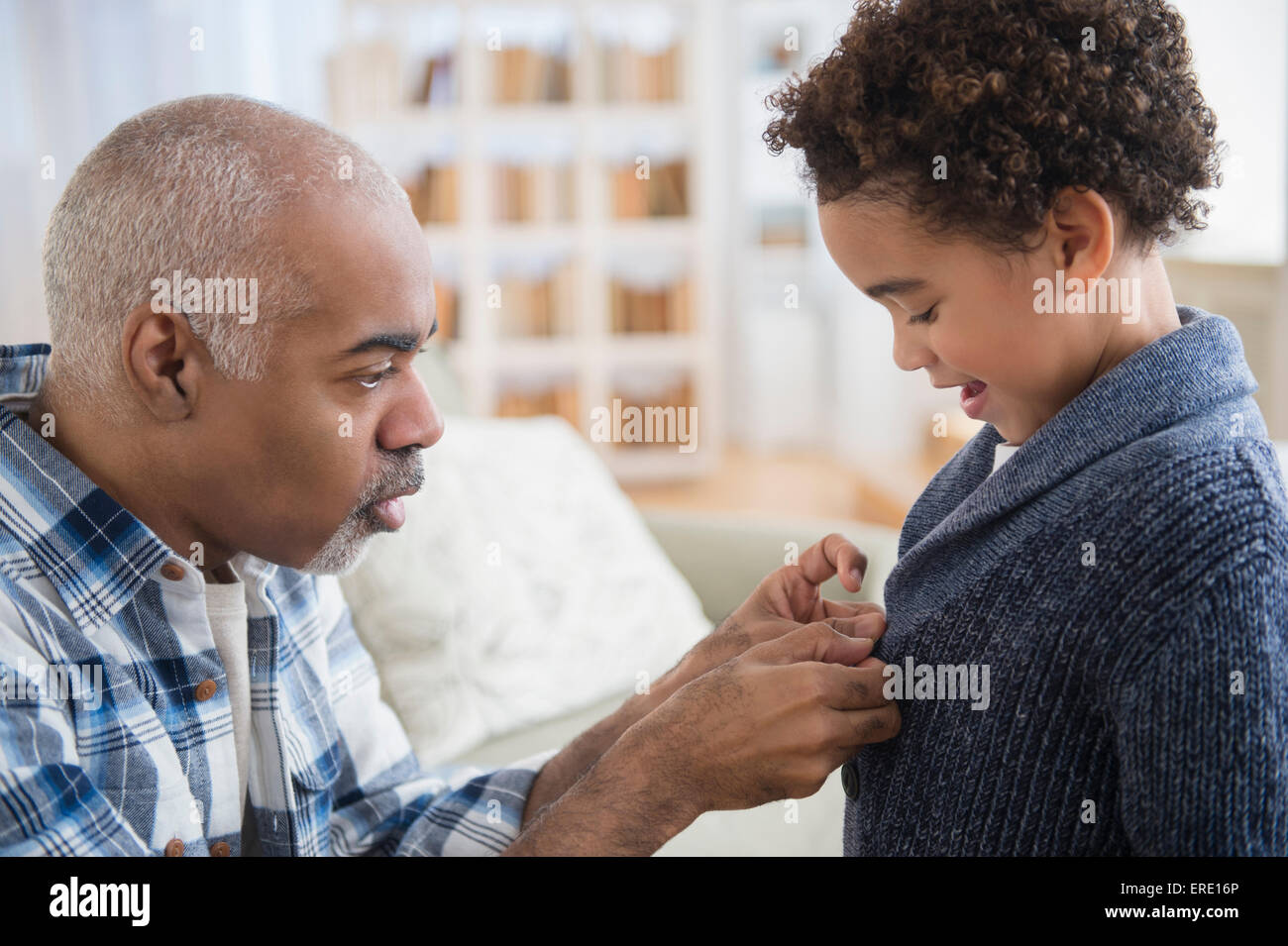 Razza mista nonno abbottonatura maglione per il nipote Foto Stock