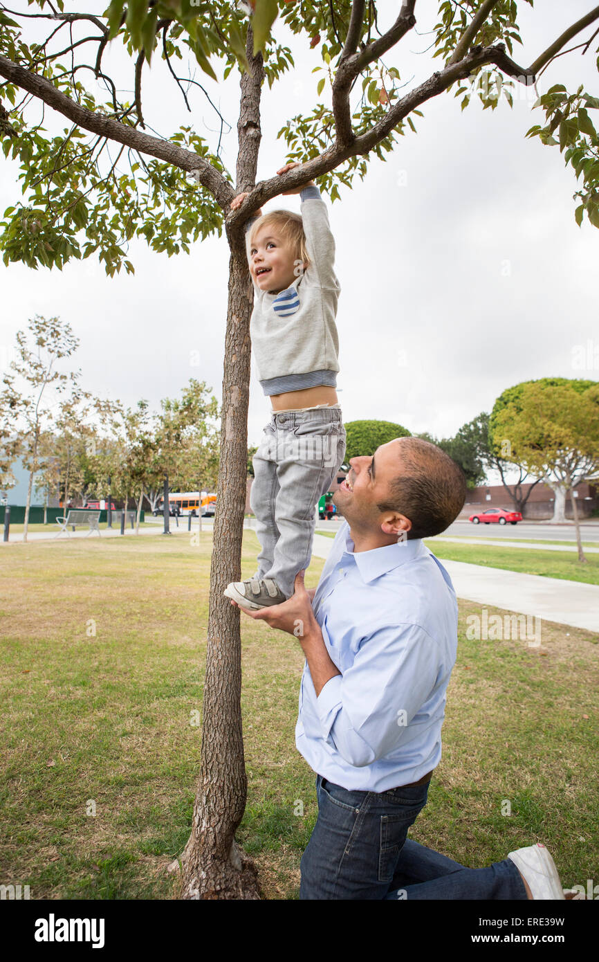 Ispanico padre e figlio giocando su albero in posizione di parcheggio Foto Stock