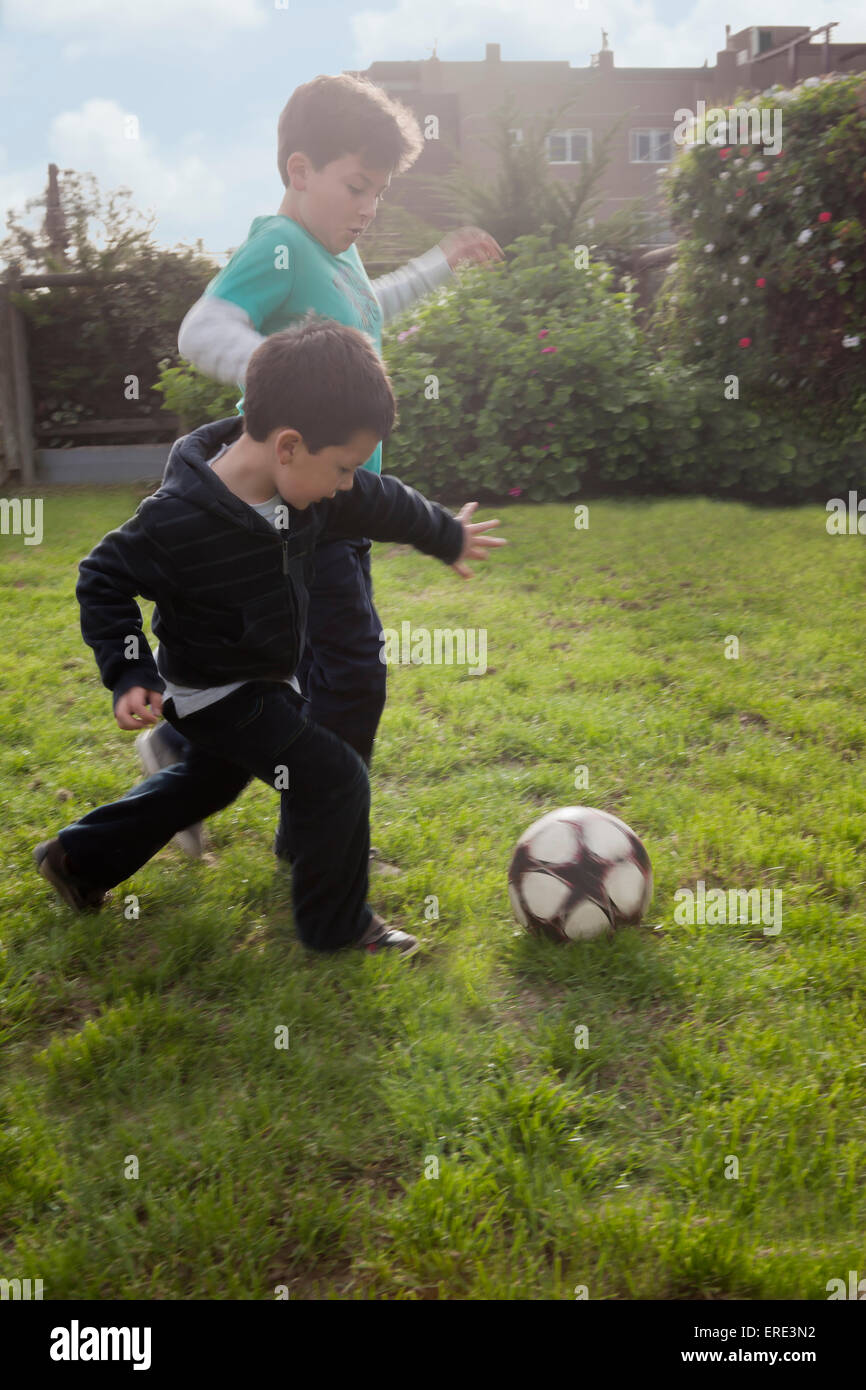 Fratelli ispanica giocando con il pallone da calcio in cortile Foto Stock