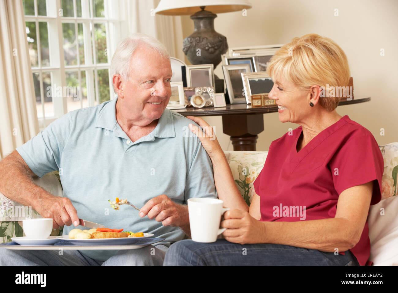 Servizio Helper Senior Uomo con pasto in casa di cura Foto Stock