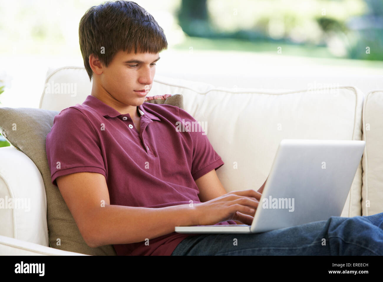 Ragazzo adolescente rilassante sul divano di casa utilizzando Laptop Foto Stock