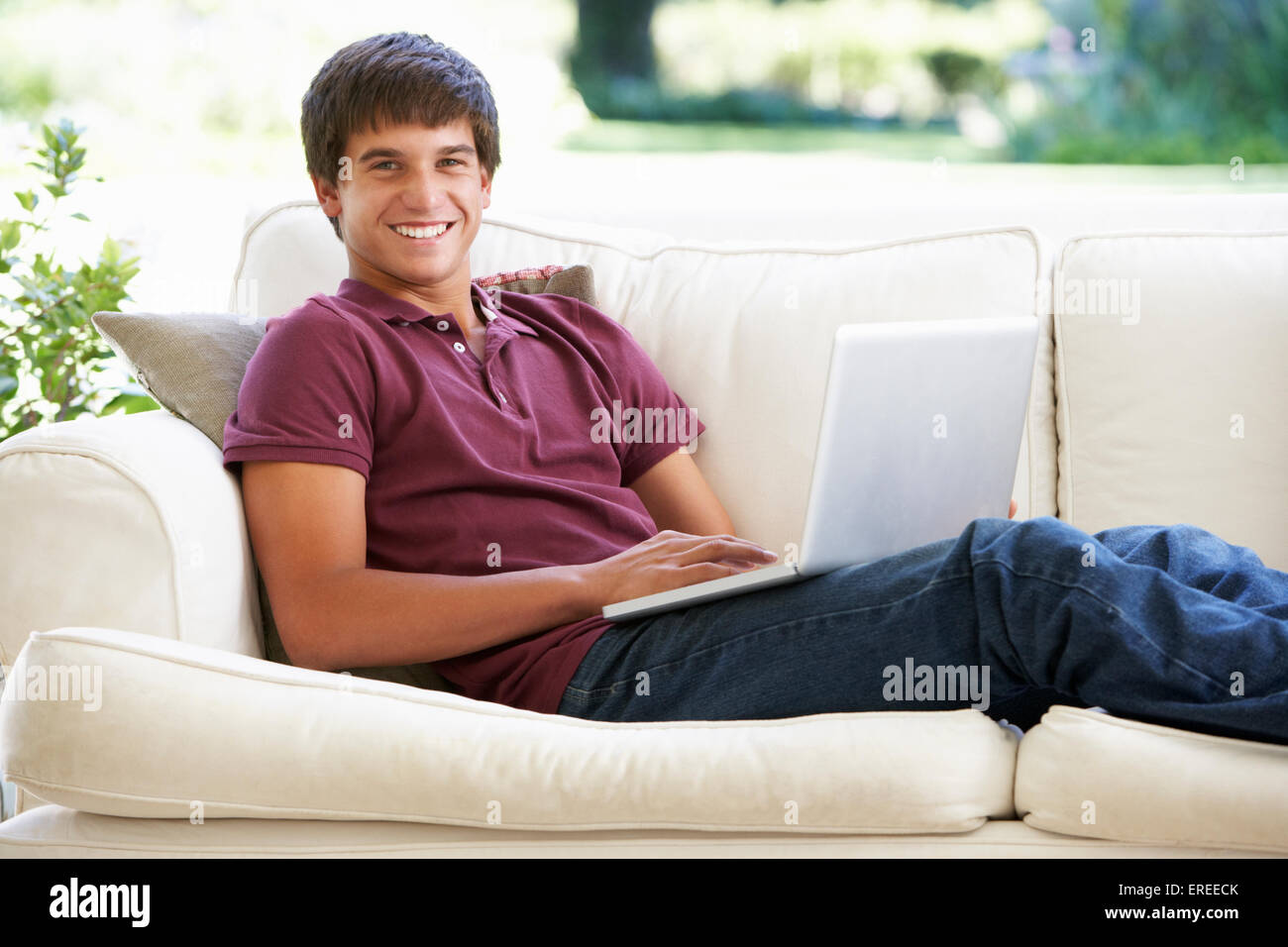 Ragazzo adolescente rilassante sul divano di casa utilizzando Laptop Foto Stock