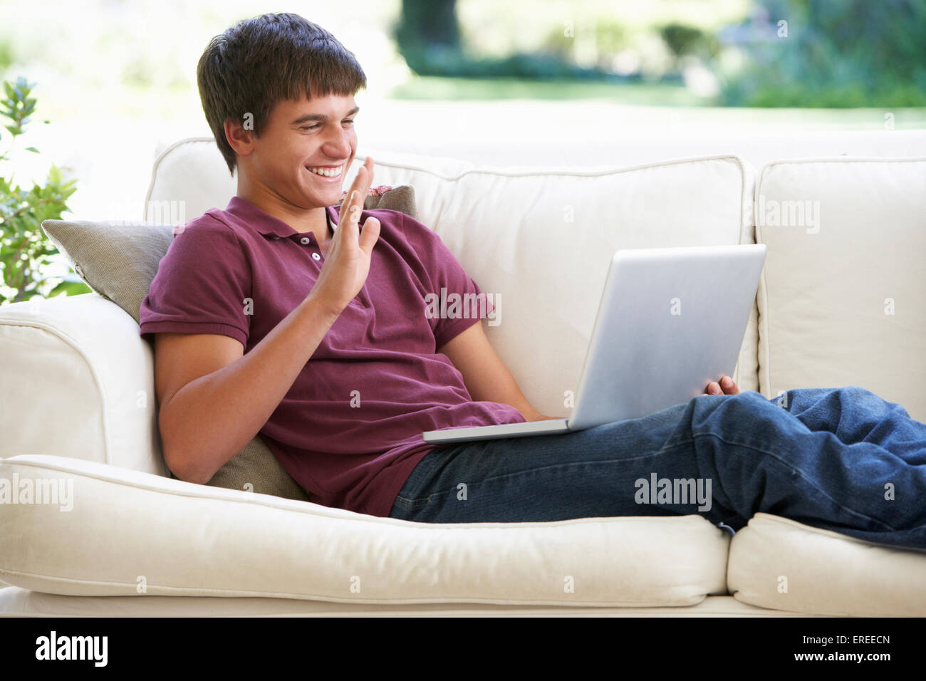 Ragazzo adolescente avente chiamata video su laptop a casa Foto Stock