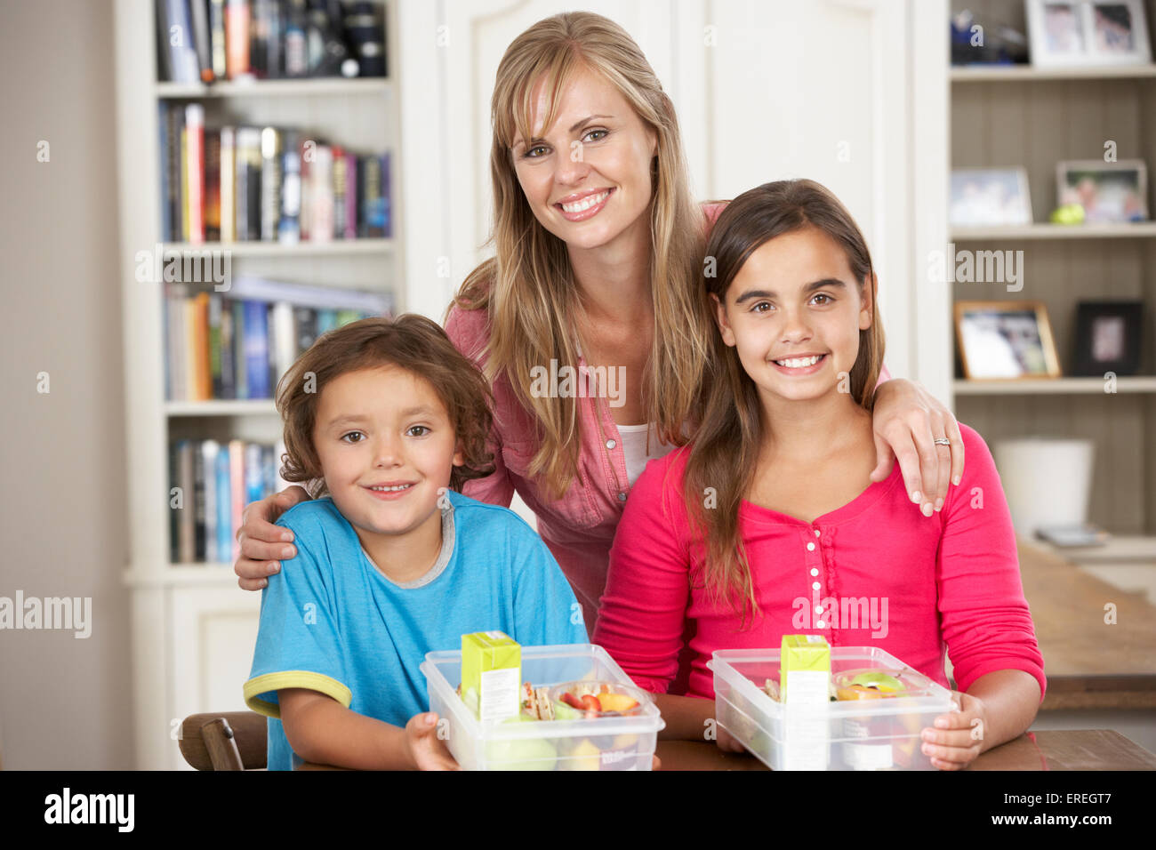 Madre dando due bambini Lunchboxes sani in cucina Foto Stock