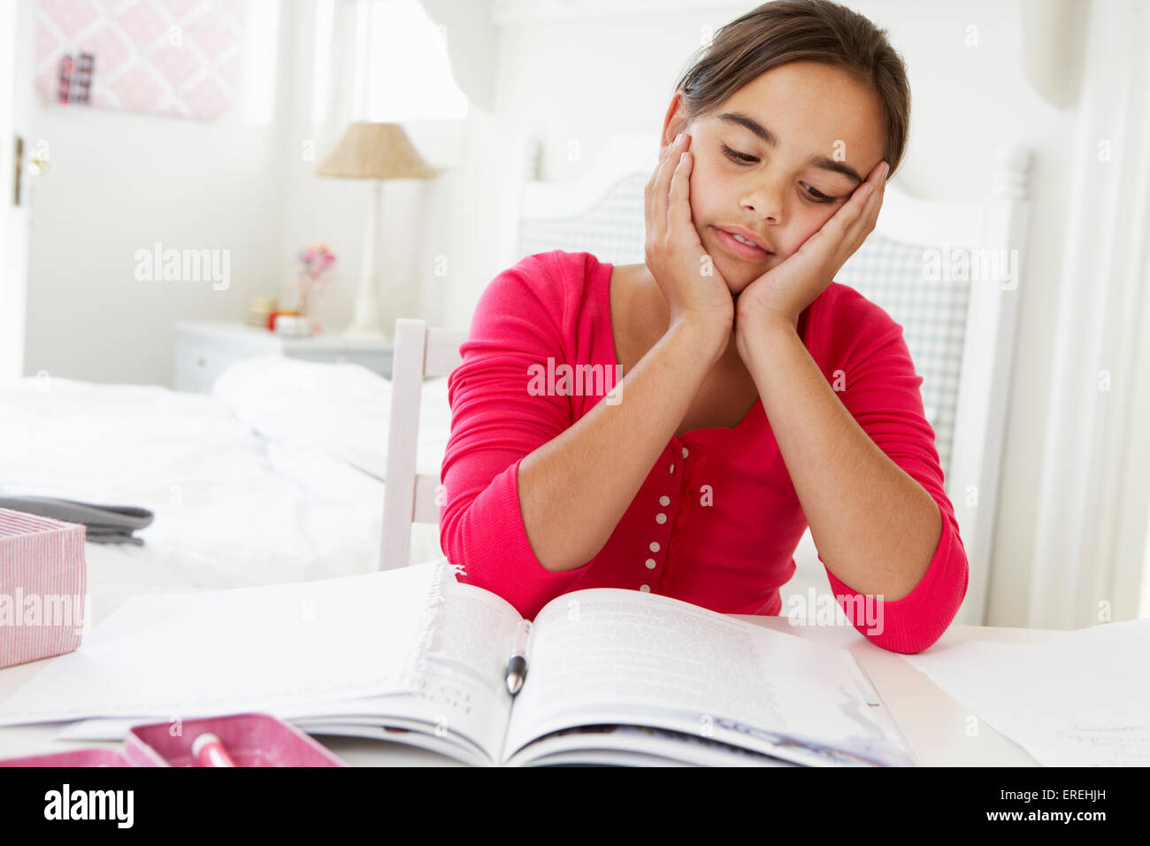 Annoiato giovane ragazza Studiare alla scrivania in camera da letto Foto Stock