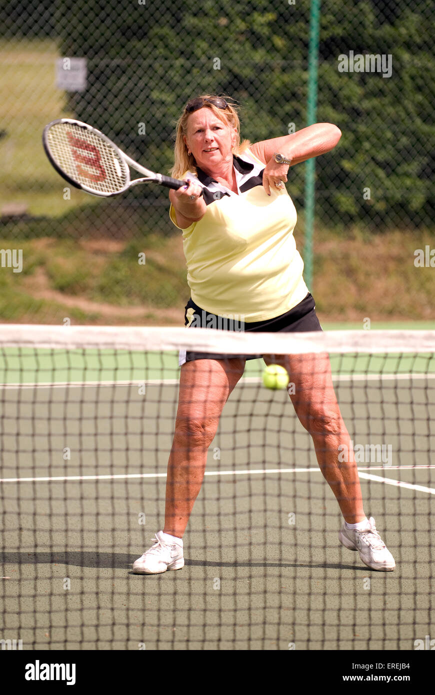 Donna anziana prendendo parte a una Carità evento tennis, Headley, Hampshire, Regno Unito. Foto Stock